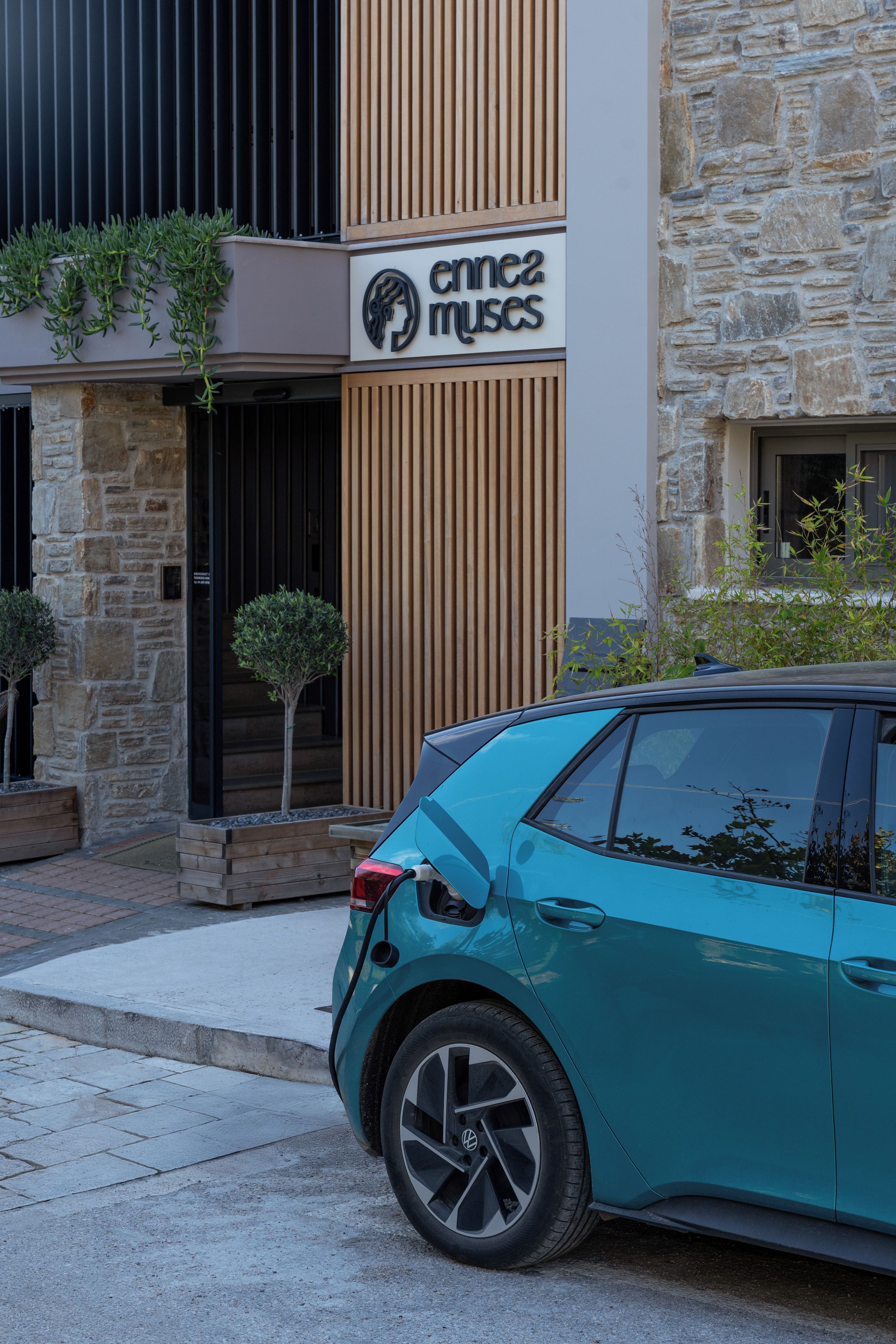 Un coche turquesa estacionado frente a un edificio con un letrero que dice 'emma muses'.