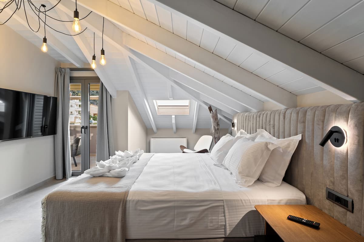 A modern bedroom with a large bed, a wooden nightstand, a TV, and a ceiling light fixture.
