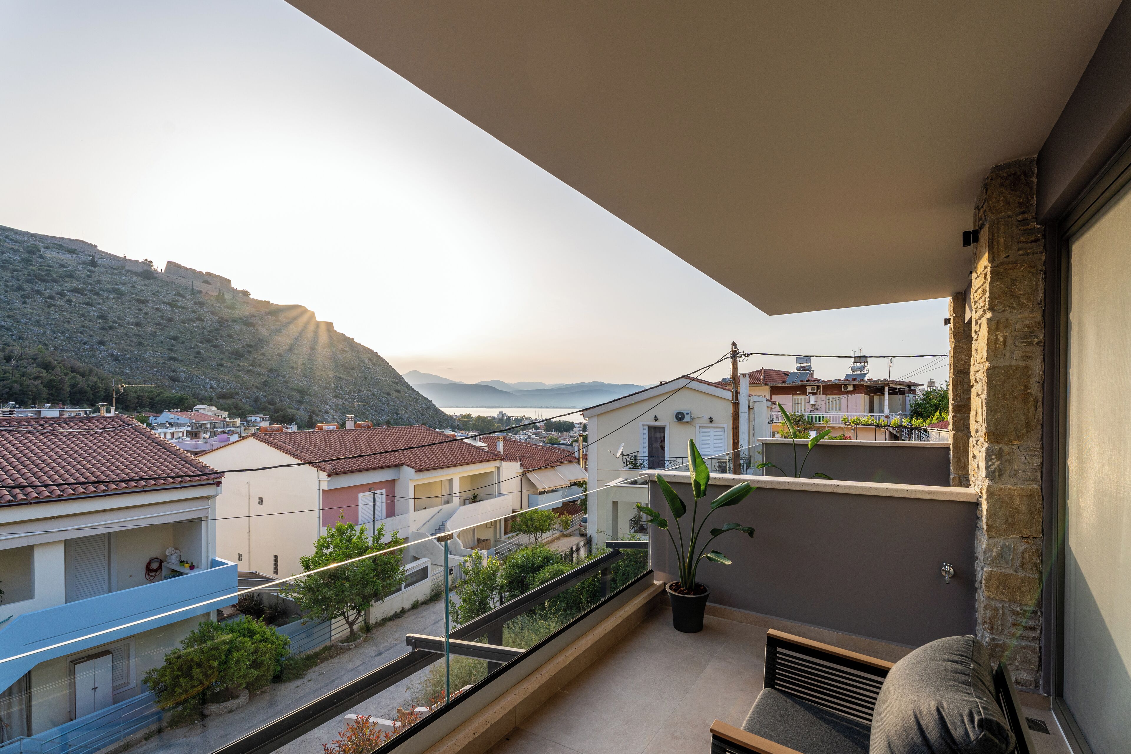 A balcony with a view of a hillside and buildings.
