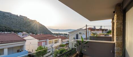A balcony with a view of a hillside and buildings.