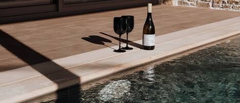Un área de piscina con un muro de piedra y una puerta de cristal.
