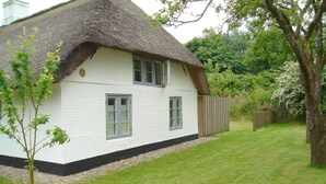 A white house with a thatched roof and a small garden. - Ferienhaus Fischerkate (St. Peter-Ording)