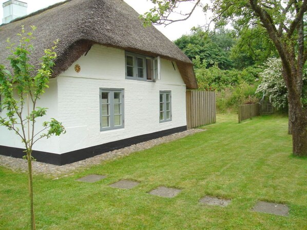 A white house with a thatched roof and a small garden. - Ferienhaus Fischerkate (St. Peter-Ording)