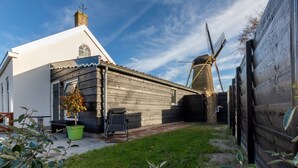 Et traditionelt hus med en mølle, en lille have og et træhegn.