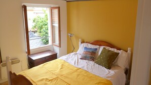 Un dormitorio con cama, ventana y vistas a zonas verdes.