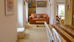 Una sala de estar acogedora con un sofá, una mesita y un sillón. Hay un globo terráqueo en una estantería y un cuadro en la pared.