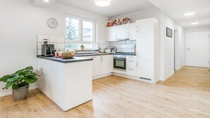 A modern kitchen with white cabinets, a central island, and a large window. - Uitzicht op de Pellenz (Nickenich)