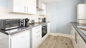 A modern kitchen with white cabinets, a built-in oven, a coffee maker, and a toaster.