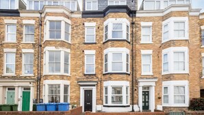 A row of terraced houses with bay windows, brick facades, and white window frames.