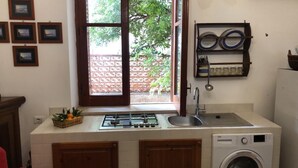 A compact kitchen with a gas stove, sink, and built-in washing machine. - 1 Bedroom Apartment in Mondello (Mondello)