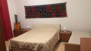 A bedroom with a bed, two bedside tables, a guitar, and a colorful tapestry on the wall. - 1 Bedroom Apartment in Mondello (Mondello)