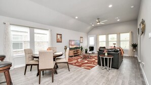 A spacious living room with a dining area, a sofa, and a TV. - Exquisite 4 Bedroom Brand New Home in Katy (Katy)