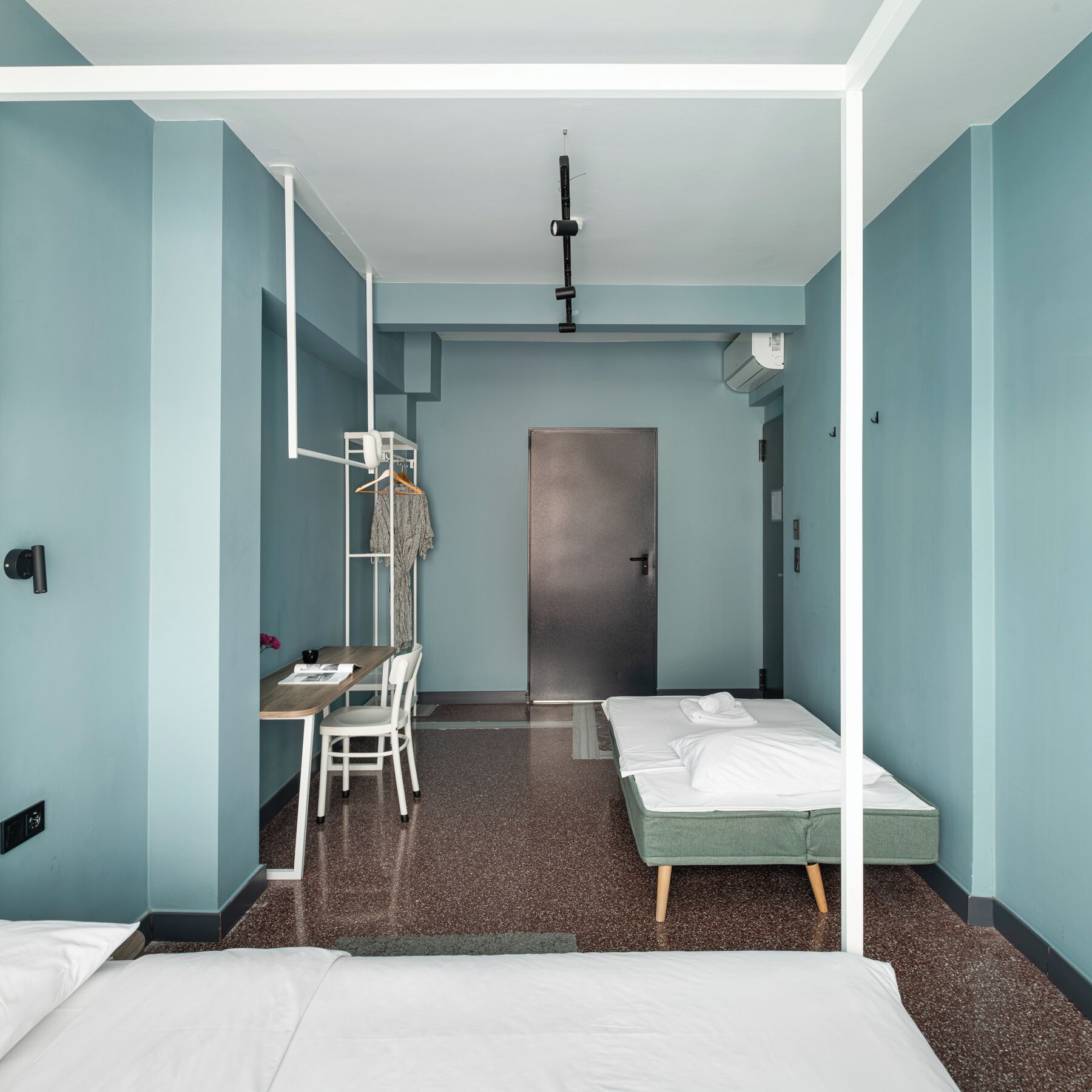 Een hotelkamer met een bed, een bureau met stoel, een kast en een deur.