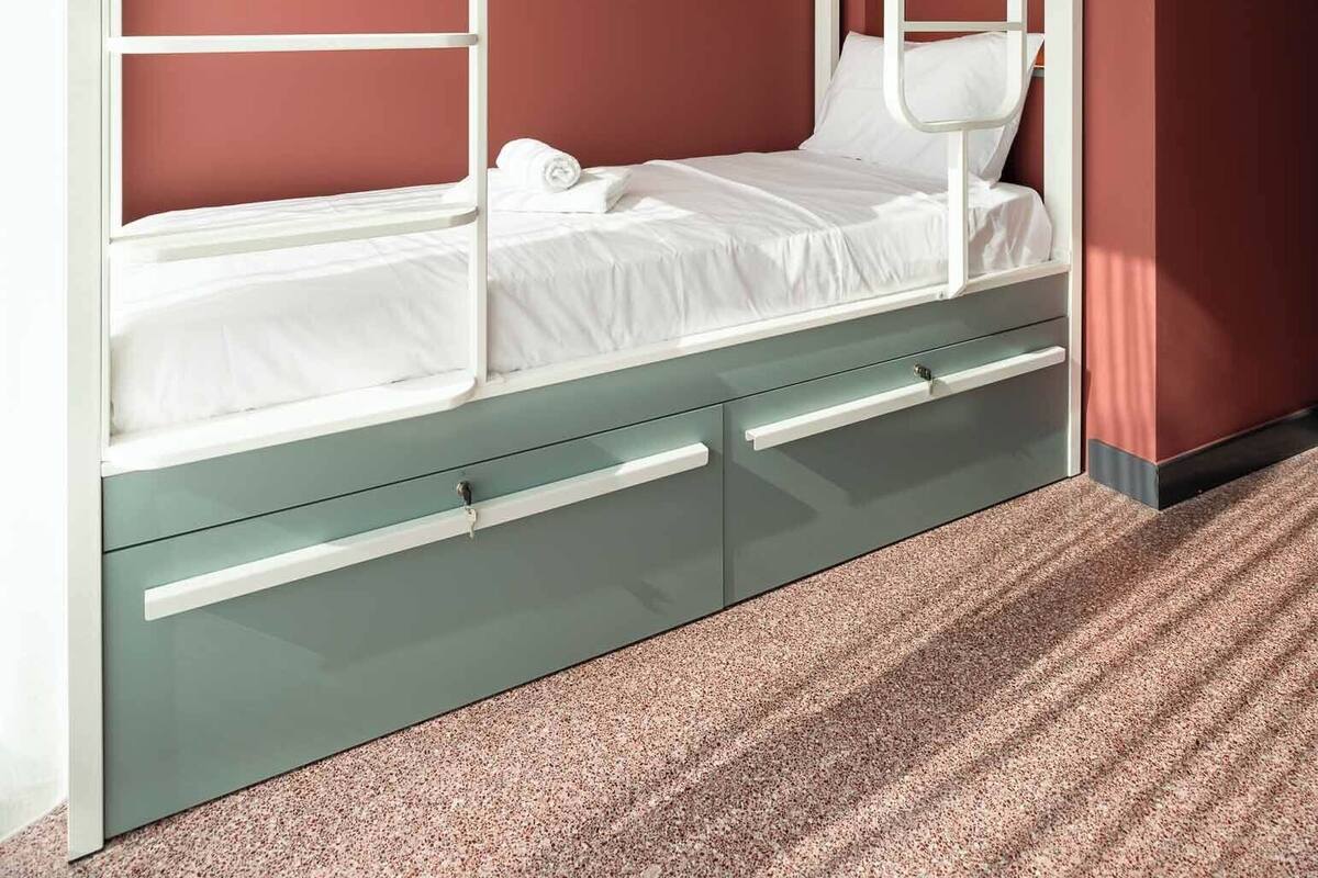 A bunk bed with two levels, a storage drawer below, and a white headboard.
