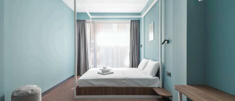 Una habitación de hotel moderna con una cama, un banco y un taburete pequeño.