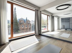 A modern room with large windows, a wooden floor, and a view of a historic building.