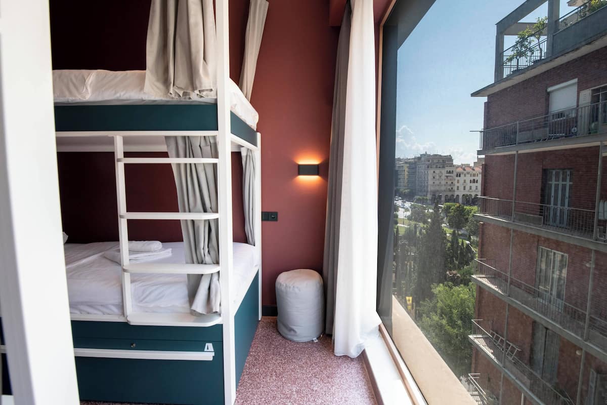 A bunk bed room with a window view of a cityscape.