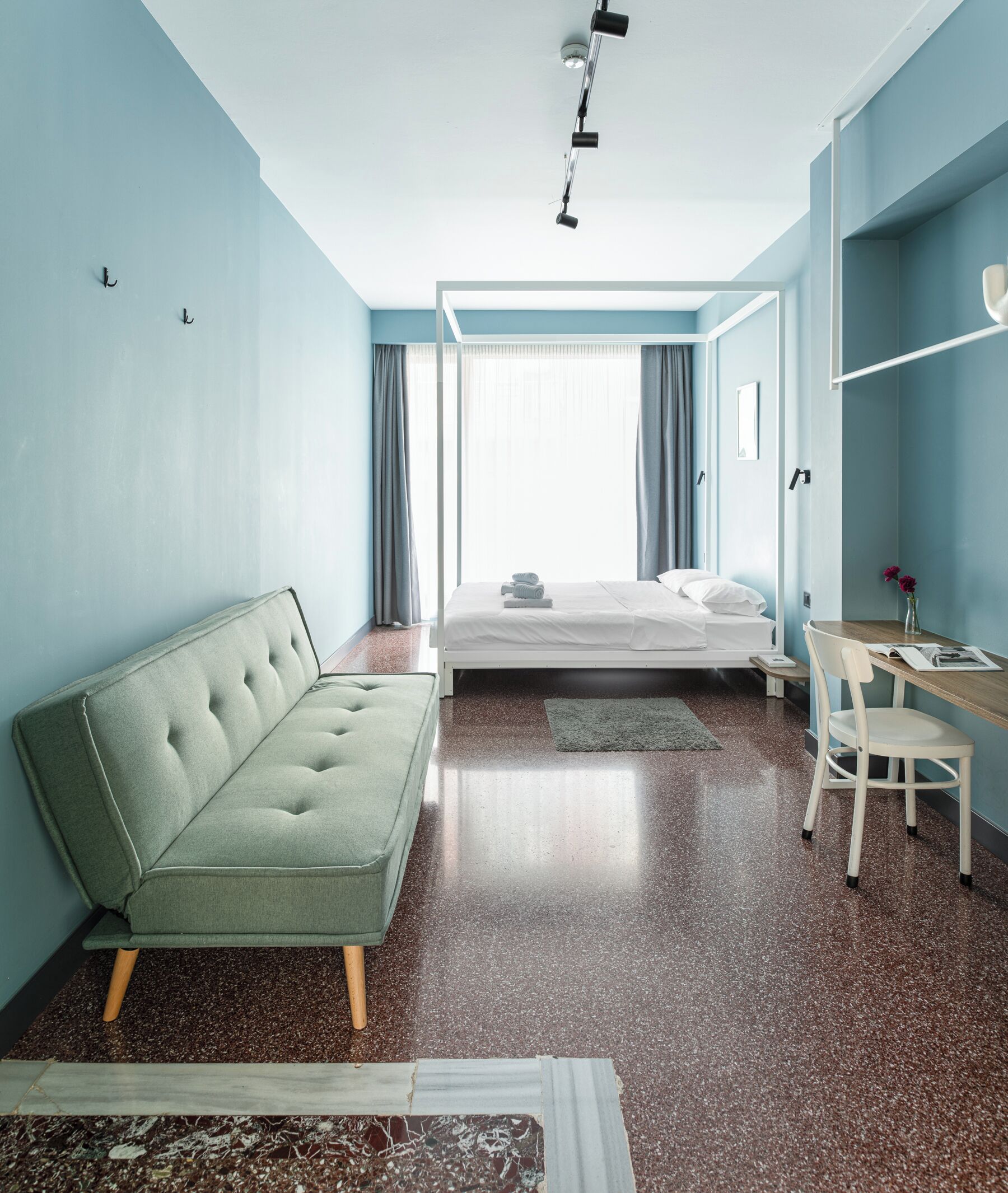 A modern hotel room with a bed, a sofa, a desk, and a chair.