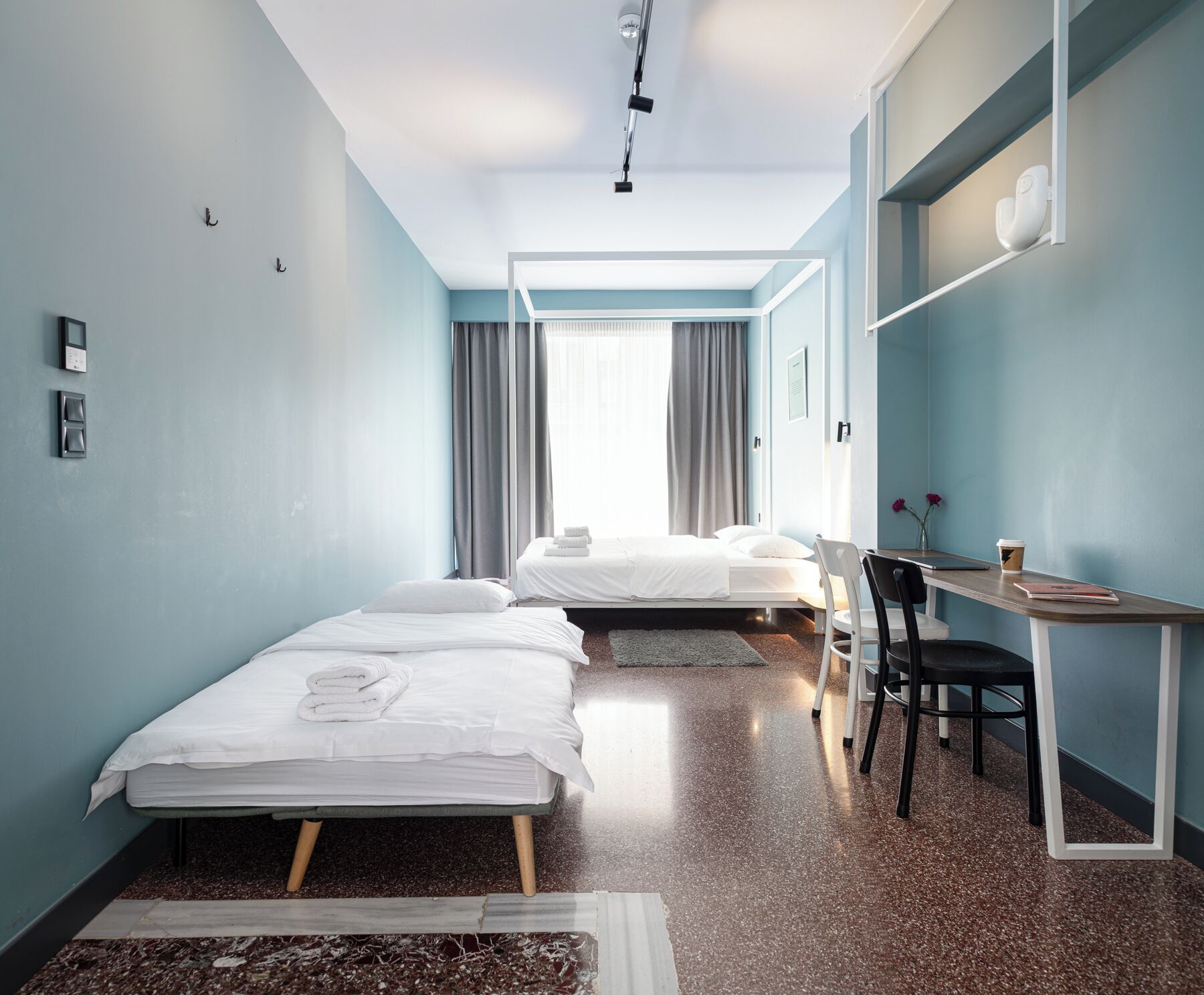 A hotel room with two beds, a desk, and a chair.