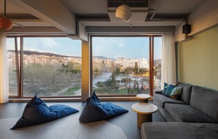 A modern living room with large windows, a sofa, a coffee table, and two bean bags.