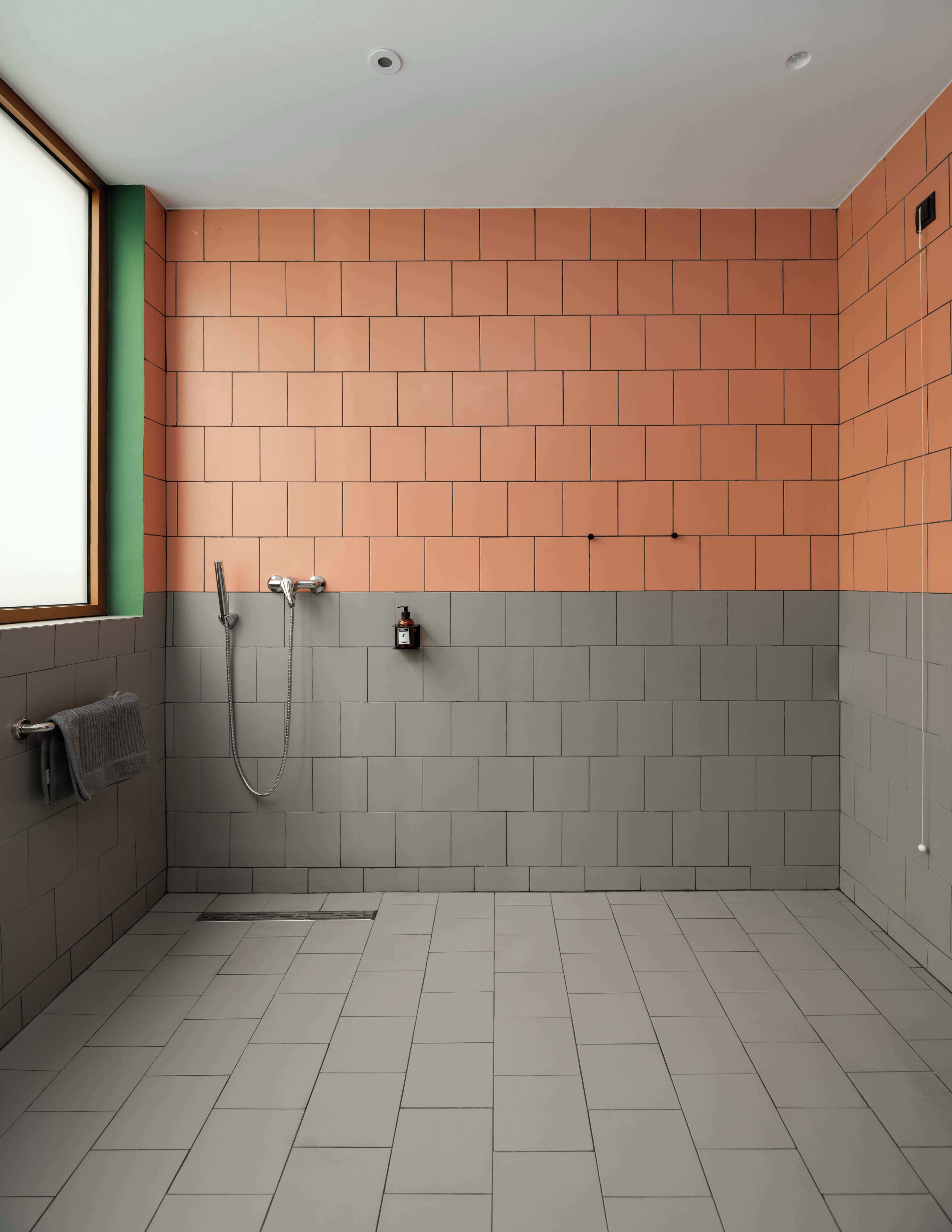 A modern bathroom with a shower, a towel rack, and a window.