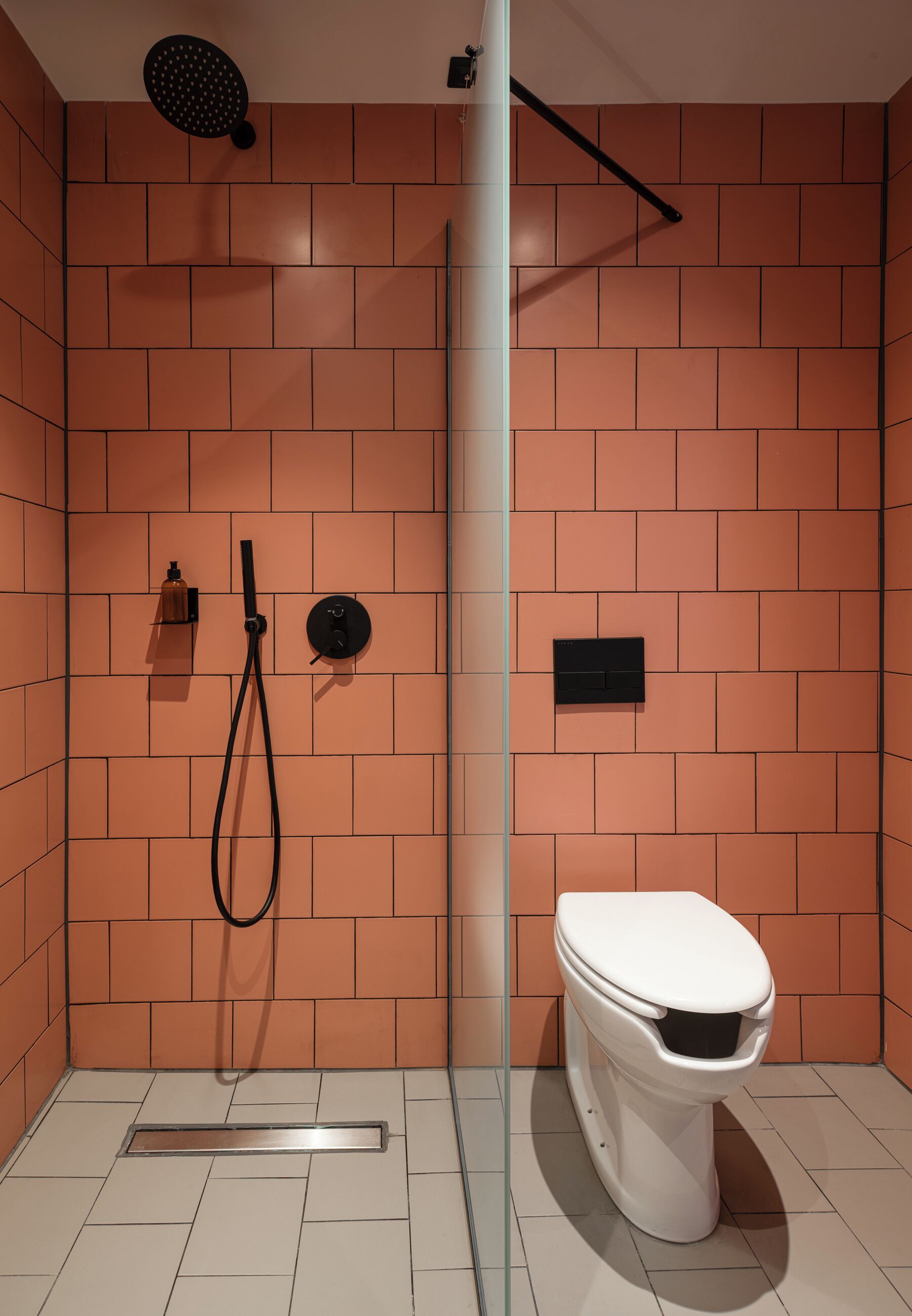 A modern bathroom with a shower, toilet, and a glass partition.