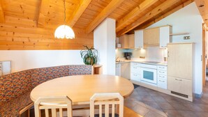 A cozy kitchen with wooden beams, a dining area with a patterned bench, and a refrigerator. - Chalet in Gattererberg Near Ski Slopes (Stummerberg)
