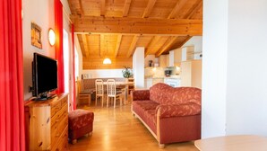 A cozy living room with a wooden ceiling, a television, a sofa, and a dining area with chairs and a table. - Chalet in Gattererberg Near Ski Slopes (Stummerberg)