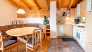 A cozy kitchen with wooden beams, a dining area with a round table and chairs, and a built-in bench. - Chalet in Gattererberg Near Ski Slopes (Stummerberg)