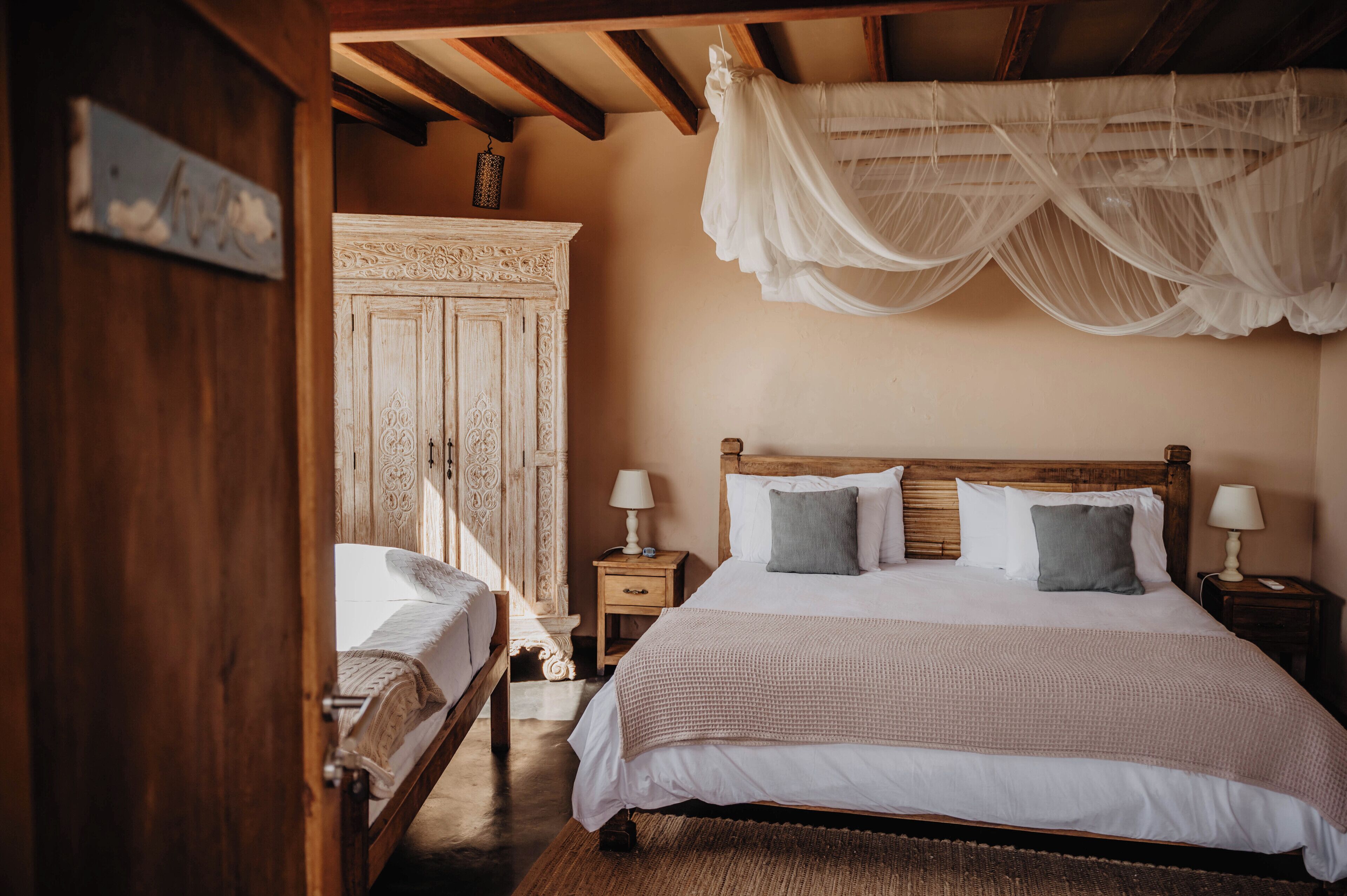 Un dormitorio con una cama grande, dos mesitas de noche con lámparas, un armario de madera y una cama con dosel.