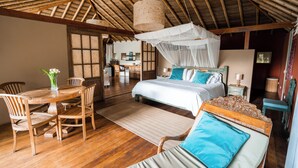 A room with a bed, a dining table with chairs, and a wooden floor. - VILLA DEL SOL  (Máncora)