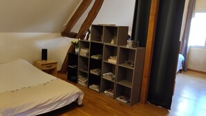 A bedroom with a bed, a nightstand, a bookshelf, and a window with curtains.