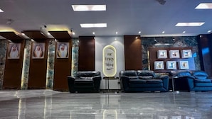 A lobby with a polished marble floor, leather seating, framed pictures on the walls, and a neon sign. - Gold Sky Avenue Hotel (Dubai)