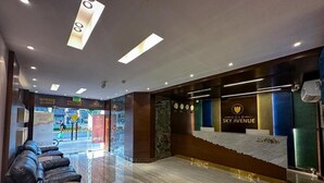 A modern lobby with leather seating, a reception desk, and a view of the street outside. - Gold Sky Avenue Hotel (Dubai)