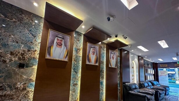 A lobby with marble walls, framed portraits, and leather seating. - Gold Sky Avenue Hotel (Dubai)