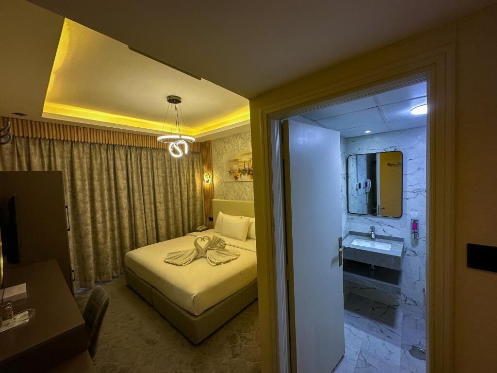 A hotel room with a bed, bedside table, and a bathroom visible through an open door.