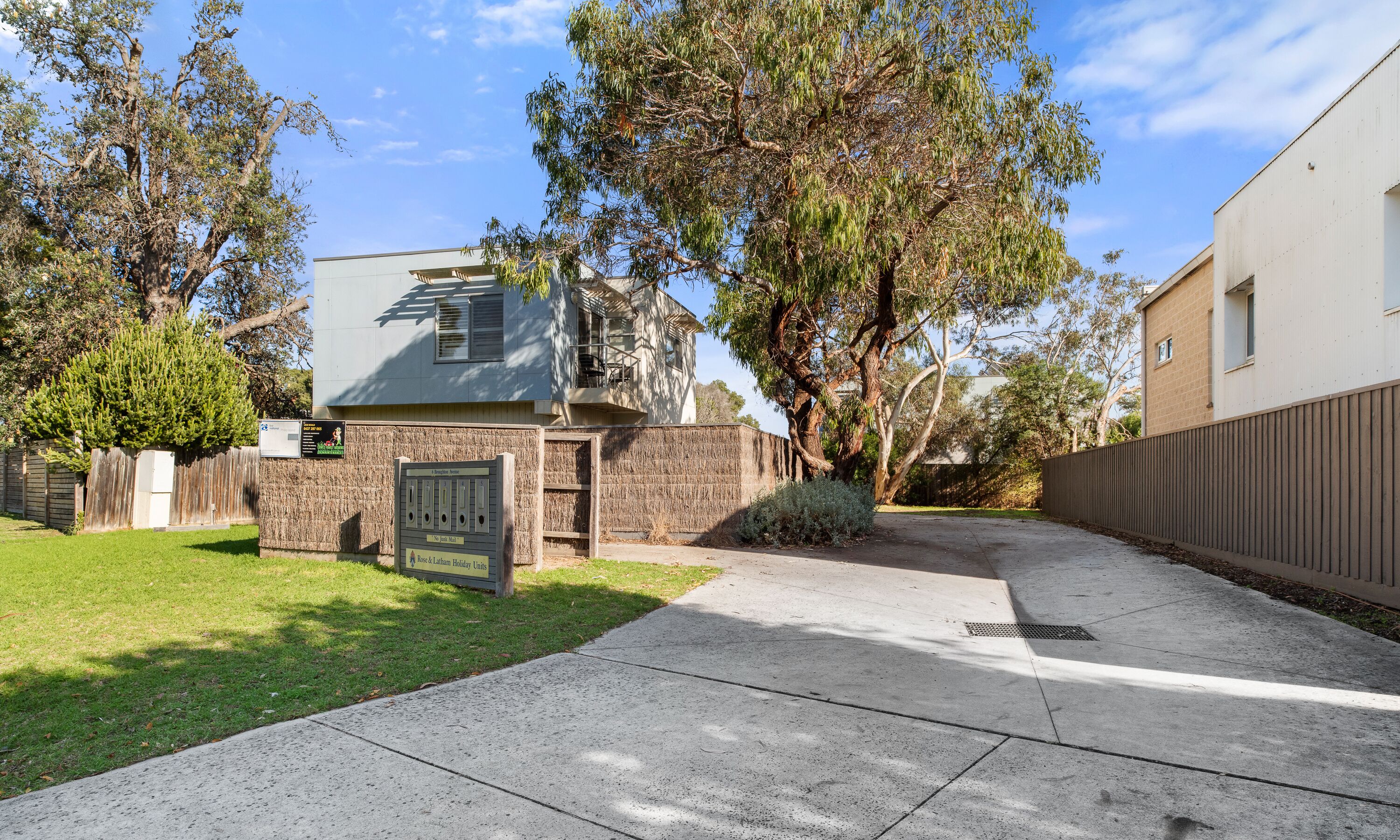 A residential property with a paved driveway, a mailbox, and a gated entrance.
