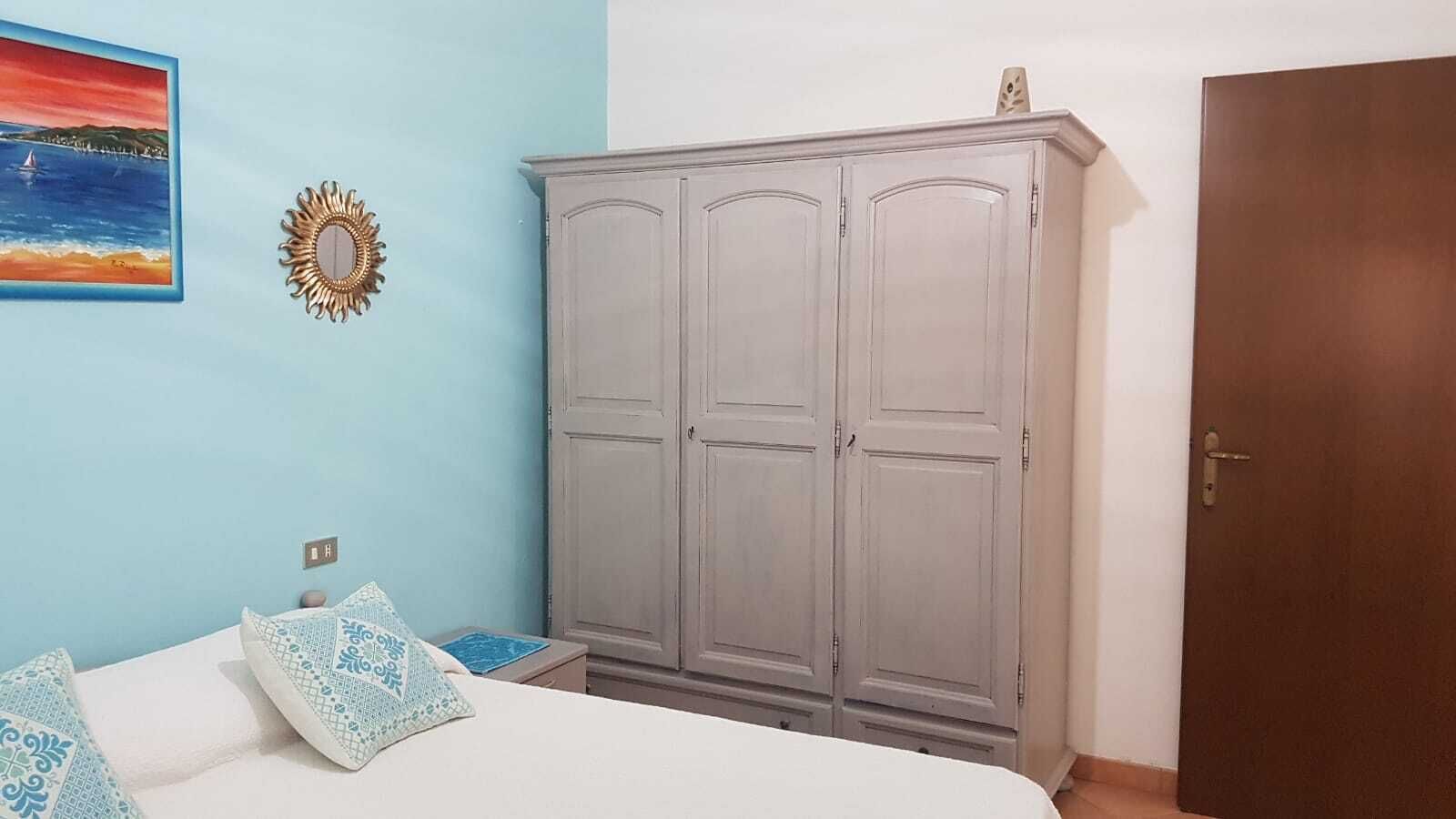Une chambre à coucher comprenant un lit, une armoire, une porte et un tableau accroché au mur.