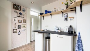 A compact kitchen with white cabinets, a black countertop, and a stainless steel trash can. - Vakantiewoning Vieverdwas (Yerseke)