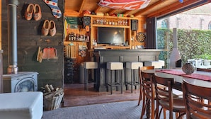 A cozy bar area with stools, a dartboard, and a television. - Characteristic House With Wellness in Augustinusga (Augustinusga)