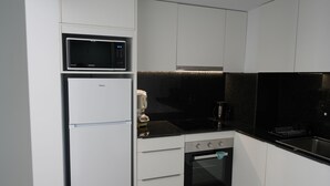 A modern kitchen with white cabinets, a black microwave, a built-in oven, and a black countertop. - Le Meilleur Appartement à Santa Margarita Immo365 (Roses)