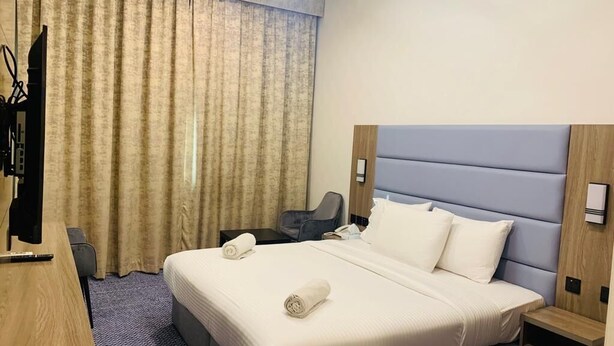 A hotel room with a large bed, a desk, a chair, and a television. - Silver Sand Hotel (Dubai)