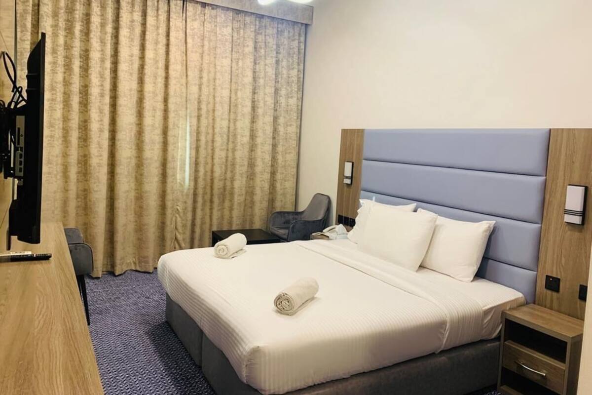Ein Hotelzimmer mit einem großen Bett, einem Schreibtisch, einem Stuhl und einem Fernseher.