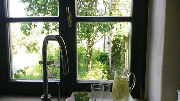 Un plan de travail de cuisine avec un évier, une carafe de limonade, des feuilles de menthe fraîche et des fraises.