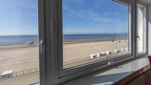 Quarto com uma grande janela com vista para a praia.