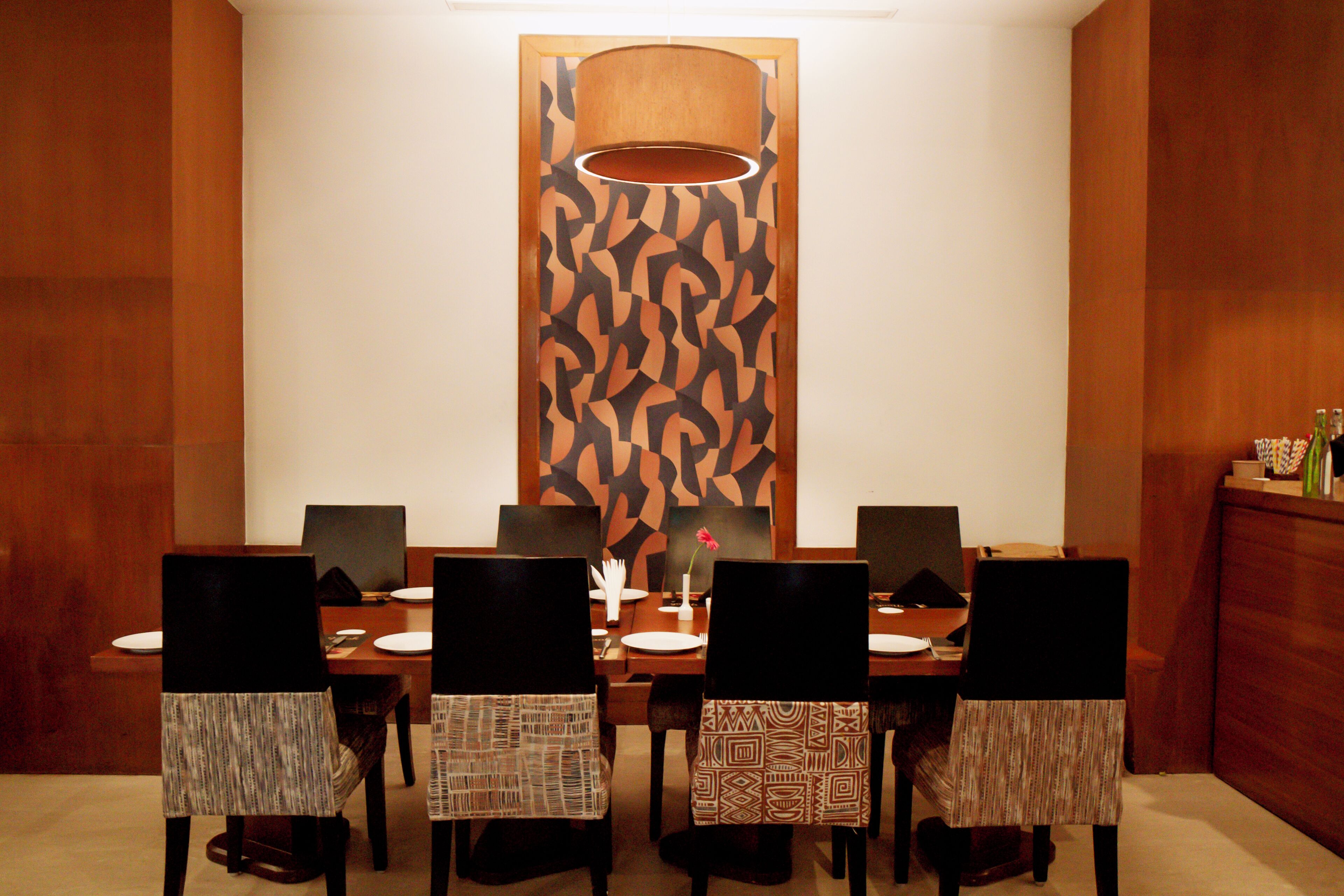 A dining area with a long table, chairs, and a patterned wall.