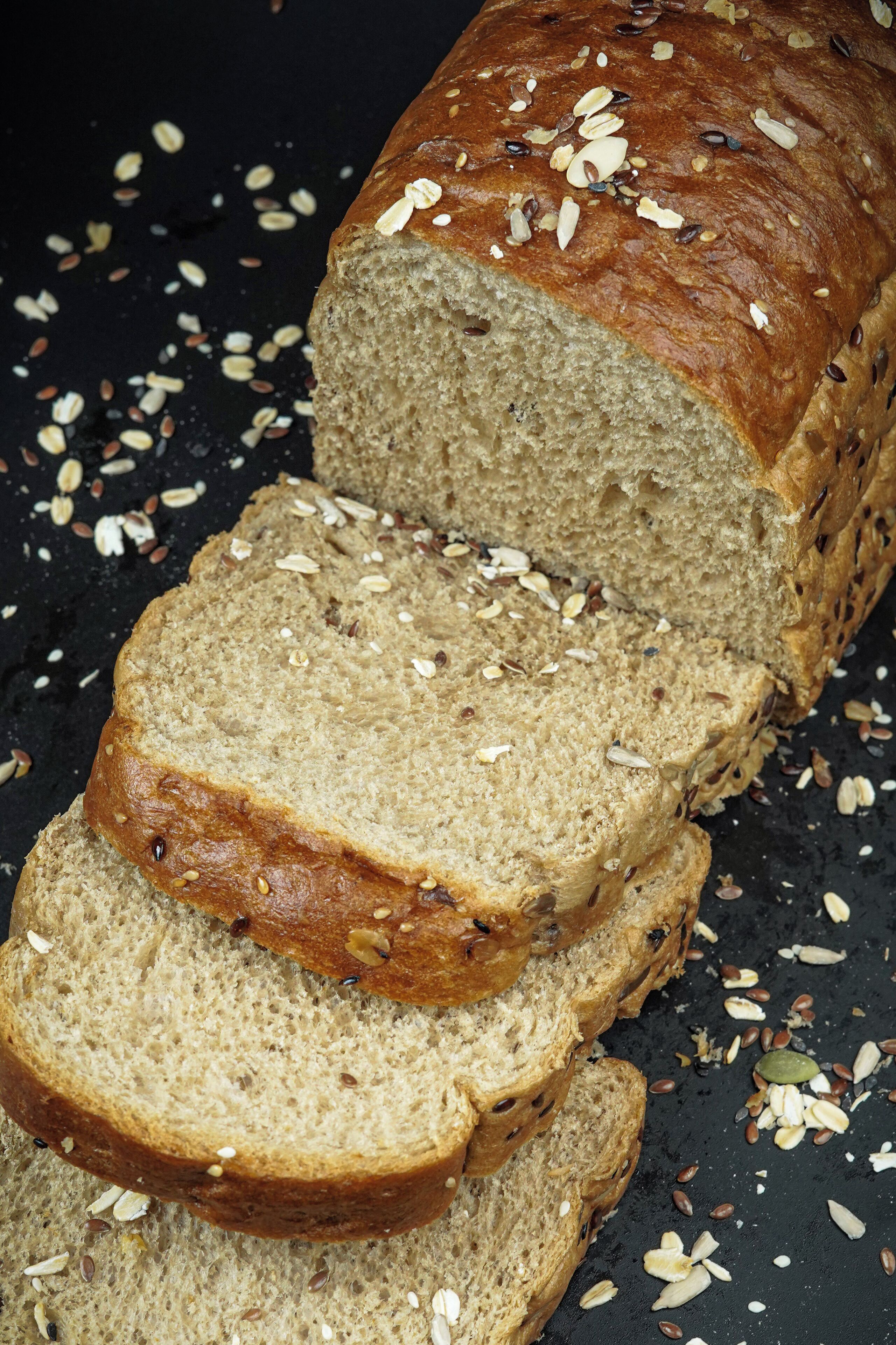 A loaf of bread with seeds on top, surrounded by scattered seeds.
