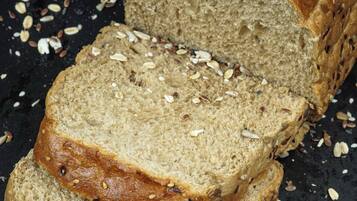 A loaf of bread with seeds on top, surrounded by scattered seeds.