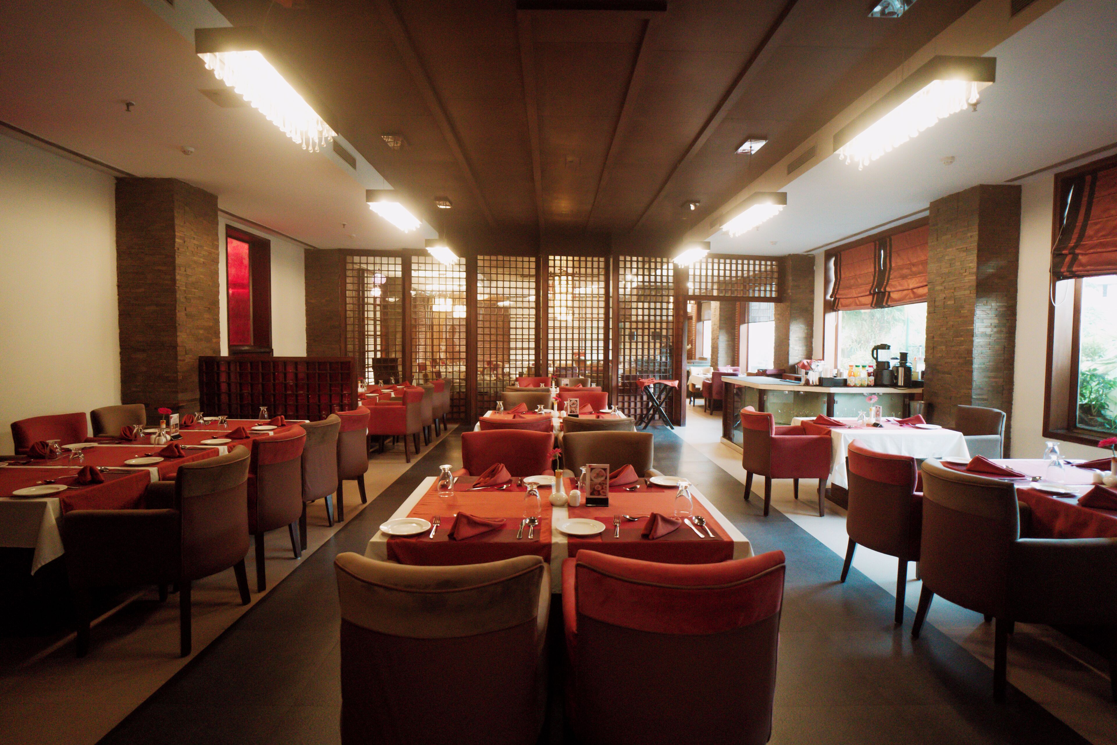 Un restaurante con varias mesas y sillas, una zona de bar y vistas al exterior.