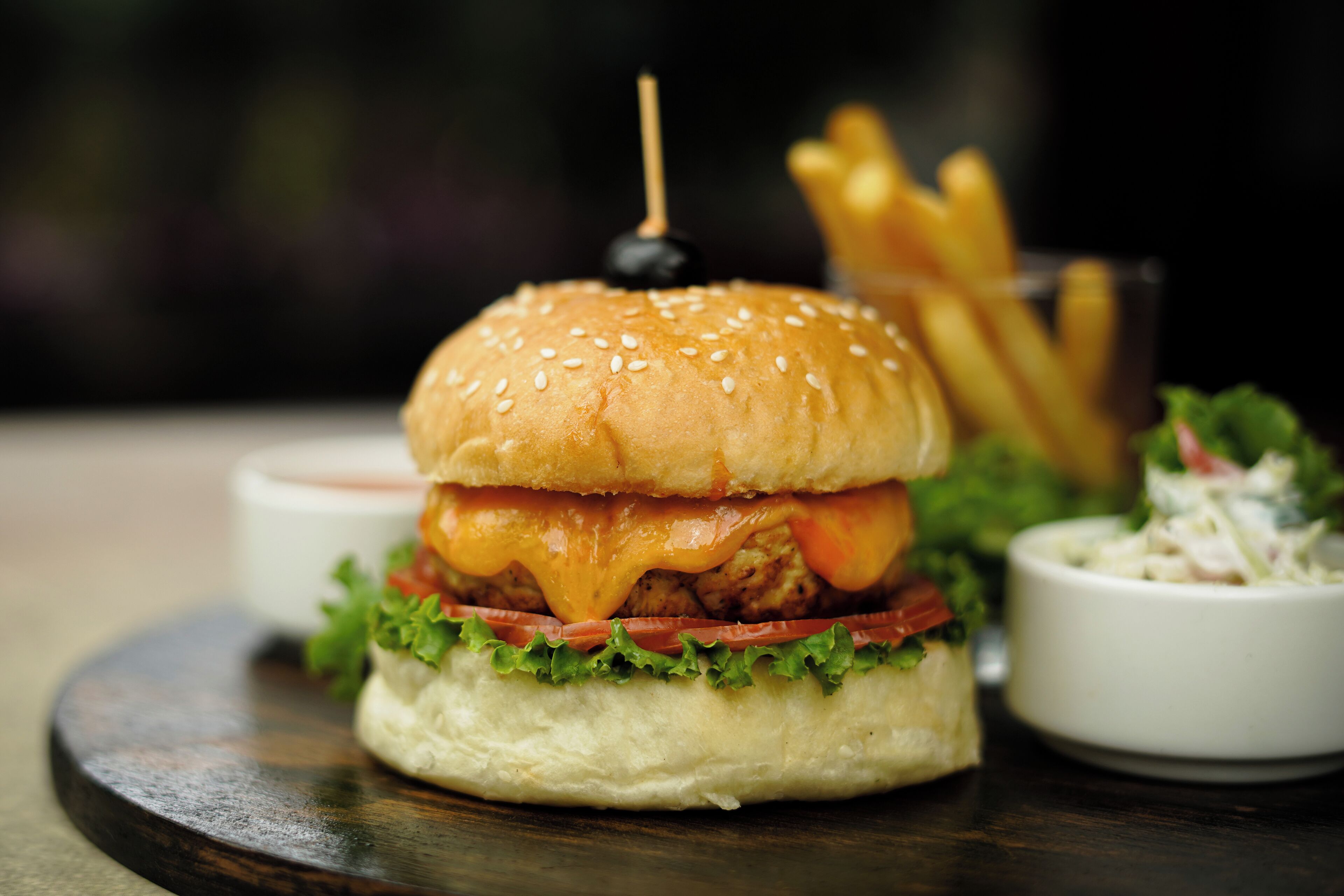 A burger with fries and a side salad on a wooden board.